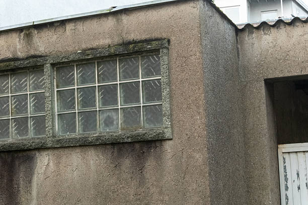 Textured concrete wall showing weathered glass block windows on an old building exterior
