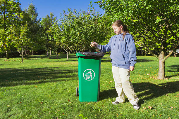 Side View Of Boy Throwing Plastic Bottle In Garbage Bin