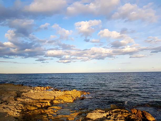 A beautiful and expressive evening scene over the Caribbean Sea near Akumal. Dramatic cloud formations spread across the sky while soft evening sunlight gently illuminates the horizon and water. The combination of light, color, and atmosphere creates a calm yet powerful tropical seascape full of mood and depth.