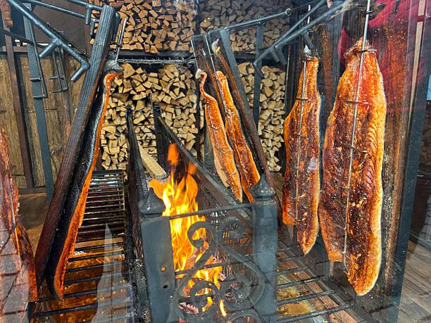 istock Large piece of salmon fish being roasted by a fire with wood stack in background at German Christmas market 2252954670