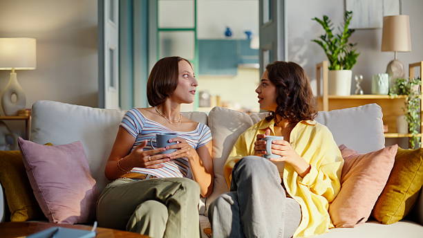 istock Sisters enjoy relaxed conversation sitting comfortable home sofa. Smiling women 2252955989