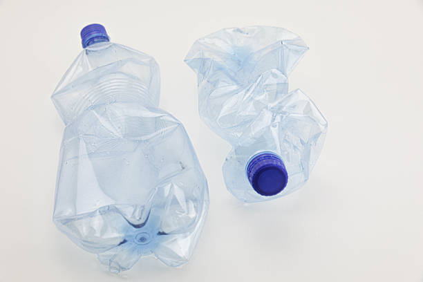 Two Crushed Plastic Water Bottles Standing On A White Background, Symbolizing Recycling, Environmental Pollution, Water Shortage, Waste Management, And Eco Awareness.