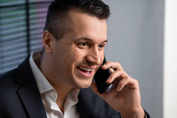 istock Businessman in suit laughing during phone call while posing in office 2252961697