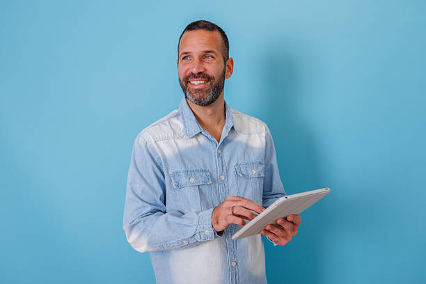 istock Man smiling and looking away while using a digital tablet for online business or casual browsing 2252972861
