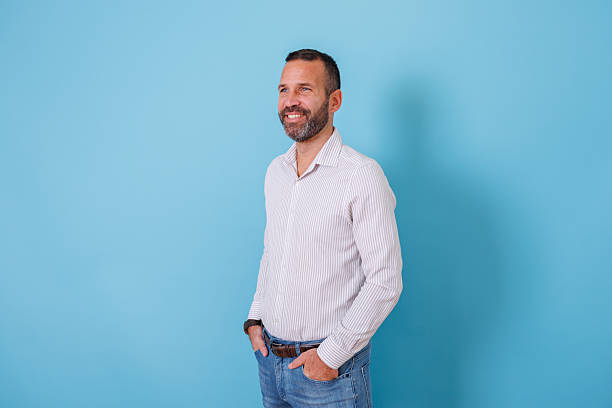 istock Confident man in a striped shirt smiling, looking away with a positive expression on a blue background 2252976990