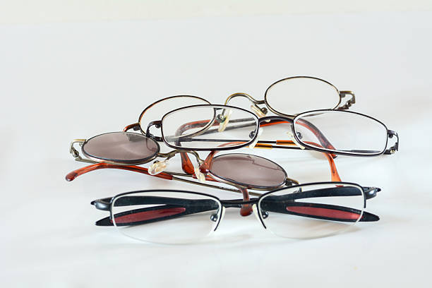Close-up of vintage round eyeglasses with thin brown frames resting on a reflective surface, with soft bokeh lights glowing in the blurred background.
