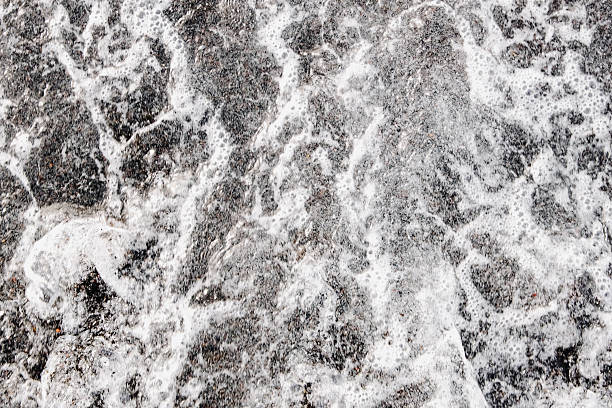 A beautiful, out-of-focus aerial close-up of a foaming Atlantic tidal wave on a black volcanic beach at sunset on an autumn evening in Tenerife. Concept art for beautiful nature backgrounds and wallpapers.