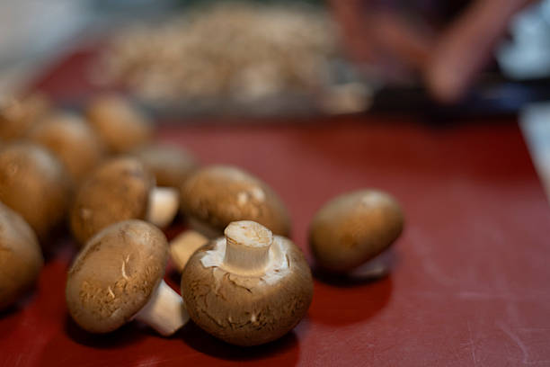 Fresh brown mushrooms are ready for chopping on a red cutting board