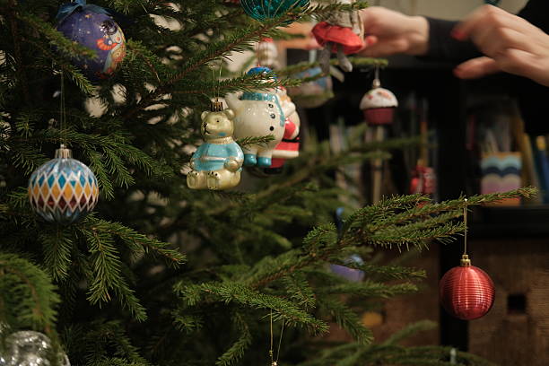 a stuffed toy, a teddy bear in a corduroy jacket, sits on a chair by the Christmas tree