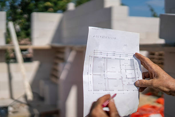 istock A construction worker holds a detailed plan while overseeing a house construction site. The project appears to have progress in the build. 2252992427