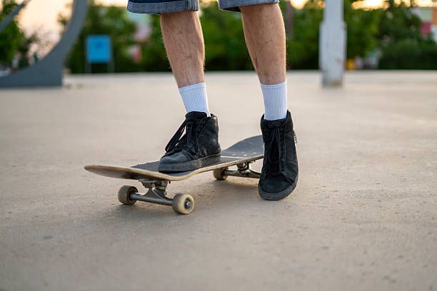 istock A skateboarder uses their leg to push off the ground while balancing on a skateboard at a park. The activity highlights street skating and skillful maneuvering. 2252992543