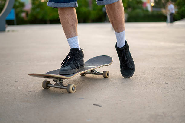 istock A skateboarder uses their leg to push off the ground while balancing on a skateboard at a park. The activity highlights street skating and skillful maneuvering. 2252992549