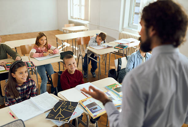 istock Group of elementary school students listening to their teacher on class. 2252992755