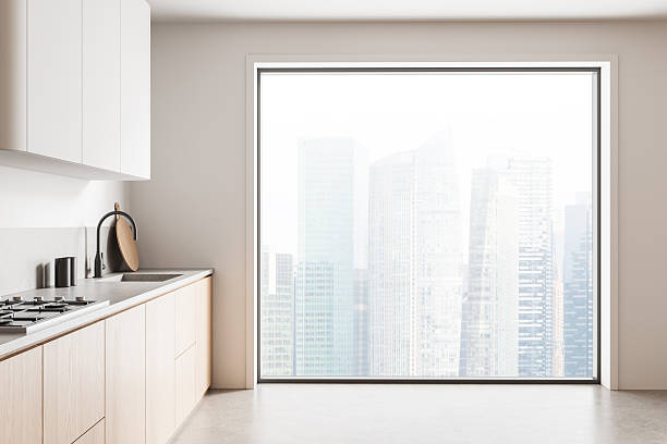 istock Modern minimalist kitchen interior with large window and cityscape view, showing clean cabinetry and neutral design tones in bright natural lighting. 3D Rendering 2253000164