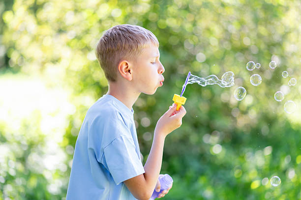 istock Teen boy blowing soap bubbles in summer park 2253000625