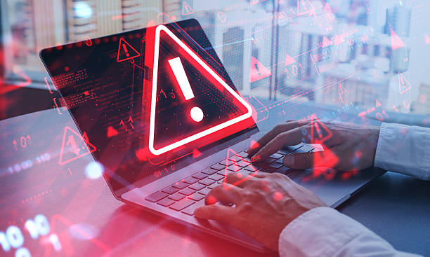 istock Cybersecurity warning concept showing alert symbol on laptop screen with red digital overlay in office environment during internet attack situation. 2253001805