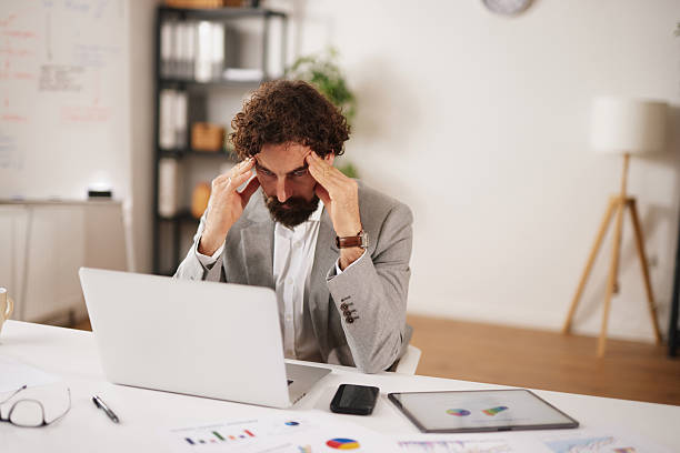 istock Office worker experiences stress due to business problems while sitting at a desk in a modern office space during the day 2253011124