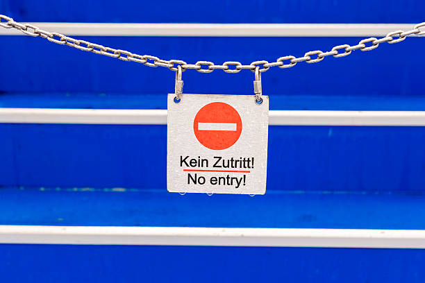 A bold red and white sign hangs from a chain across a bright blue staircase, clearly indicating no entry to passersby on a dreary day. The vibrant colors contrast with the grey sky.