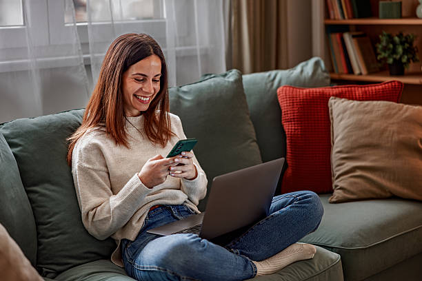 istock Young happy woman having a video call on laptop while sitting on sofa 2253013580