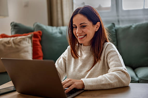 istock Young happy woman having a video call on laptop while sitting on sofa 2253013622