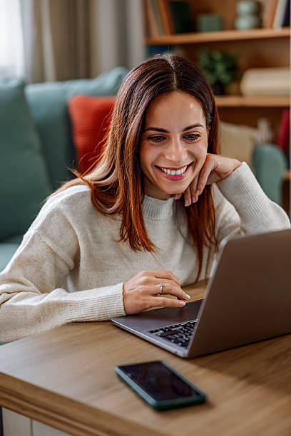 istock Young happy woman having a video call on laptop while sitting on sofa 2253013623