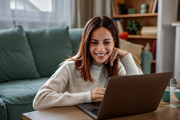 istock Young happy woman having a video call on laptop while sitting on sofa 2253013624