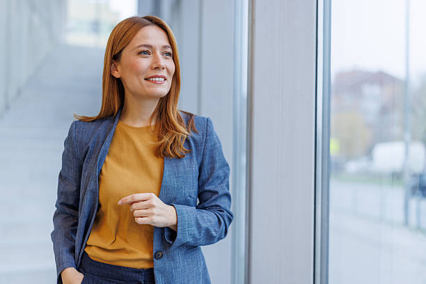 istock Businesswoman standing in office, looking confidently at window 2253017399