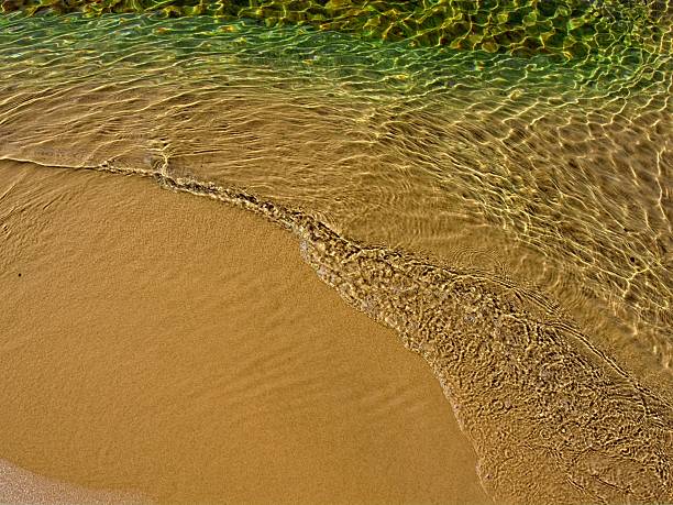 Detailed abstract of water washing over a fine sand beach on Lake Superior. Fresh water and sand texture of small ripples moving across brown sand at Sand Point beach just east of Munising Michigan at Pictured Rocks national lakeshore.
