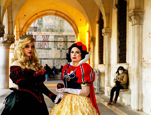 People in traditional Venetian carnival costumes pose for a photo in a historic courtyard during the Venice Carnival. Venice, Italy – 02.16. 2025