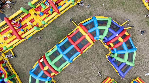 Aerial view of a colorful inflatable obstacle course on grass.