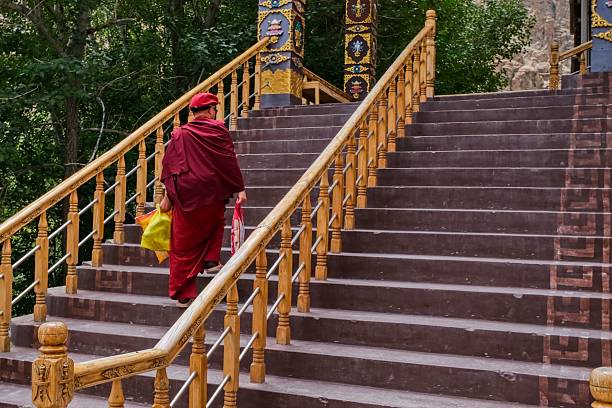Ladakh,India,19.08.2025: Buddhist monk in traditional red robes walks up staircase at Hemis Monastery in Ladakh, India. Daily monastic life, spiritual practice and movement within Tibetan Buddhist monastery architecture