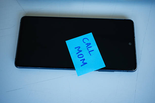 Pink adhesive paper with text that says phone number written on it, stuck on a brown board