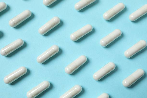 istock White medical capsules on blue background 2253032912