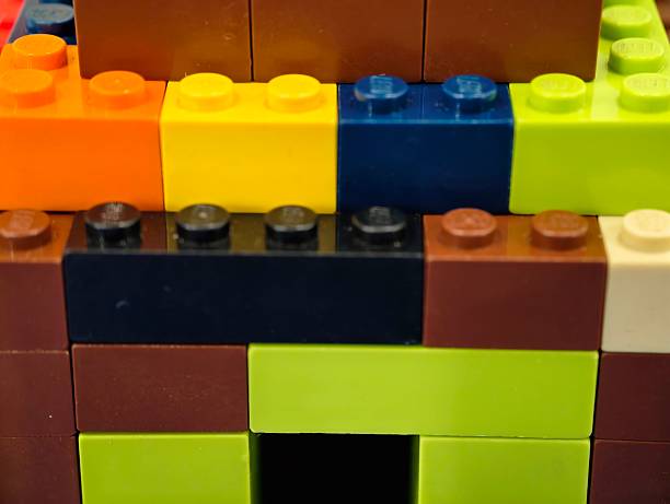 Bright Plastic Brick Facade With Doorway, Closeup Of Stacked Colorful Studs Forming Playful Miniature House,
