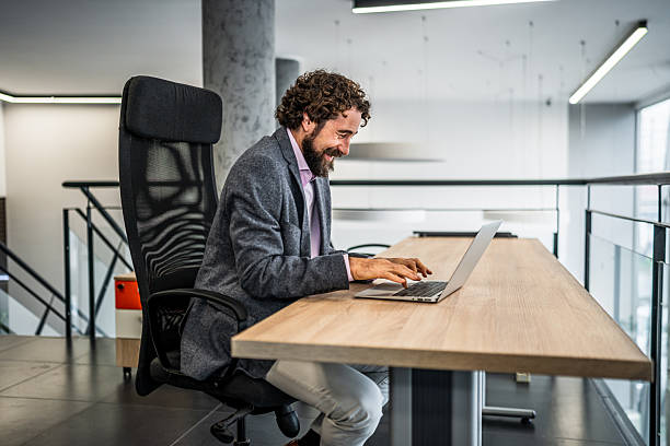 istock Happy businessman using laptop in modern office 2253033674