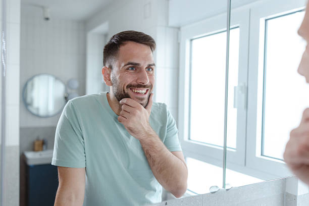 istock Smiling man in a bright bathroom reflecting on his morning routine and self care 2253034322