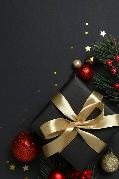 istock Beautiful gift box tied with bow and Christmas decorations on black background 2253036475