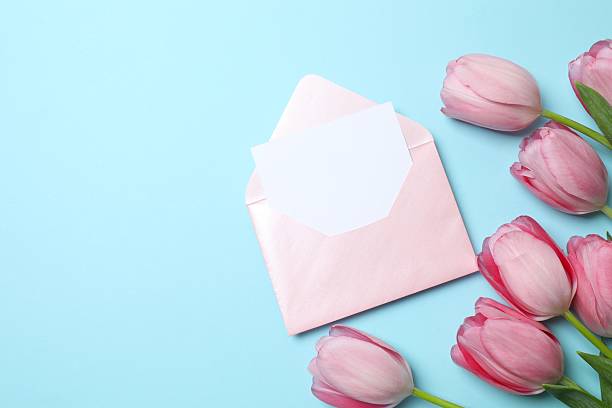 istock Beautiful fresh tulips with paper envelope on blue background 2253037631