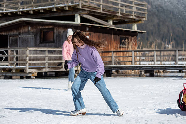 A girl in a purple sweater skates on the natural ice rink Weissensee in the Austrian Alps, warming up around a yellow backpack.