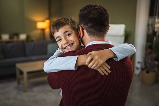 istock Happy boy hugging his father smiling at home 2253047297