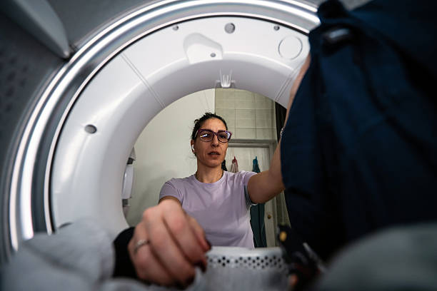 istock Woman loading garments into washing machine, viewed from inside 2253048501