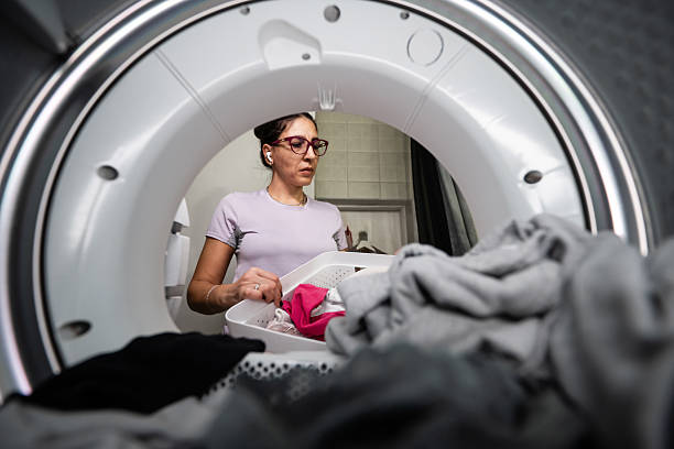istock Woman loading laundry into dryer at home, doing chores 2253048545