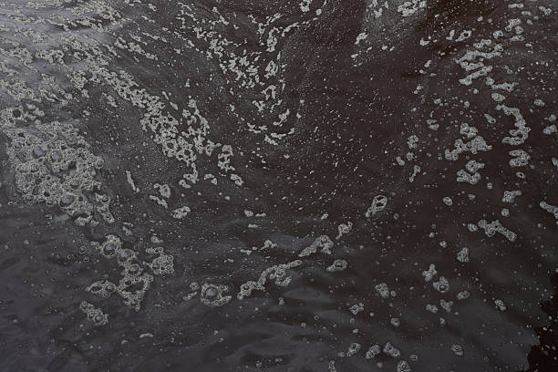 Dark brown foaming contaminated water. Polluted dark water view from above.