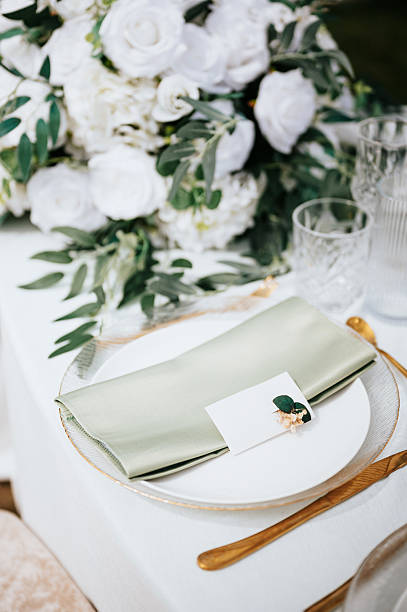Elegant place setting is shown, featuring a floral centerpiece, a personalized card, and a napkin with a pearl ring