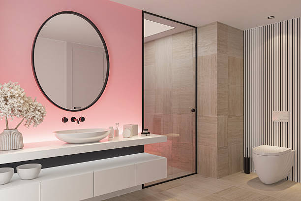 istock Stylish Bathroom with Pink Accent Back Lit Wall and Round Mirror 2253054560