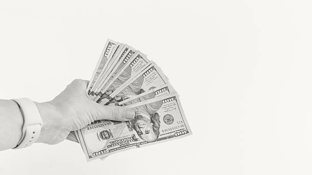 istock Hand Holding a Stack of Hundred Dollar Bills on Cream Backdrop. Financial Success Concept. Colour of the year Cloud Dancer 2253054603