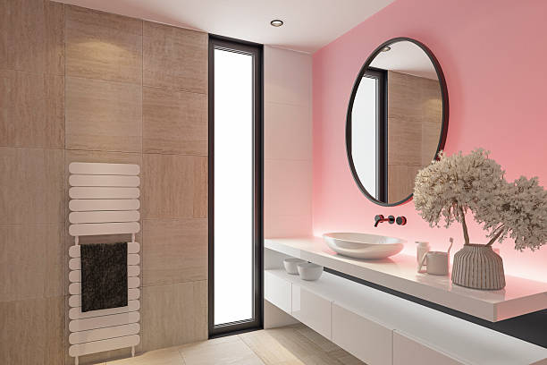 istock Stylish Bathroom with Pink Accent Back Lit Wall and Round Mirror 2253054629