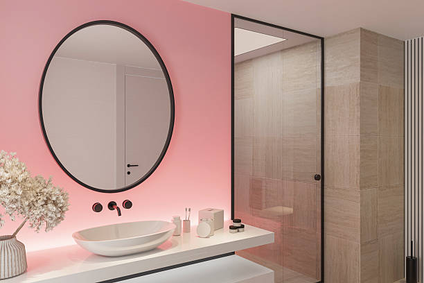 istock Stylish Bathroom with Pink Accent Back Lit Wall and Round Mirror 2253054709