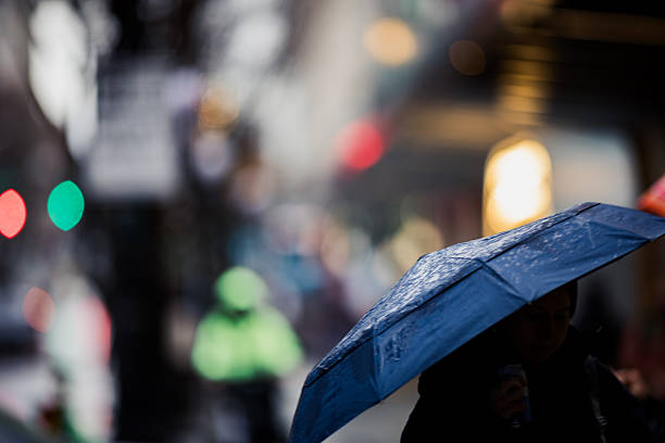 istock Umbrella in busy crowded rainy city 2253055762