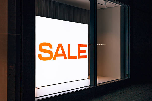 Bright illuminated sale sign displayed inside a minimal retail storefront window during evening hours.